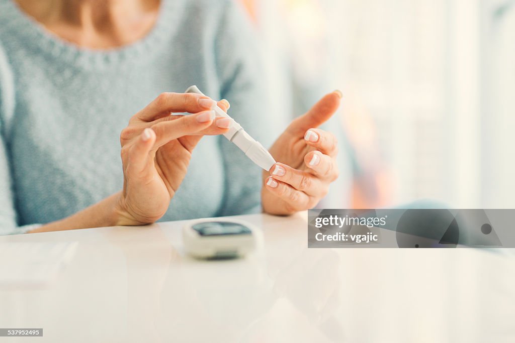 Mature Woman Doing Blood Sugar Test at home.