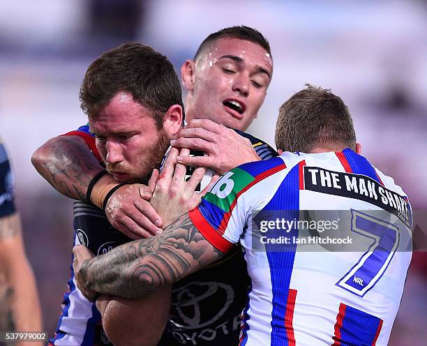 Gavin Cooper of the Cowboys is tackled by Trent Hodkinson of the Knights during the round 13 NRL match between the North Queensland Cowboys and the...