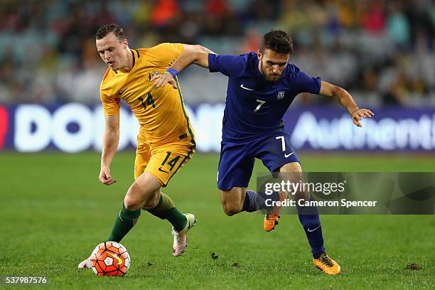 Ioannis Giaaniotas of Greece is tackled by Brad Smith of the Socceroos during the international friendly match between the Australian Socceroos and...