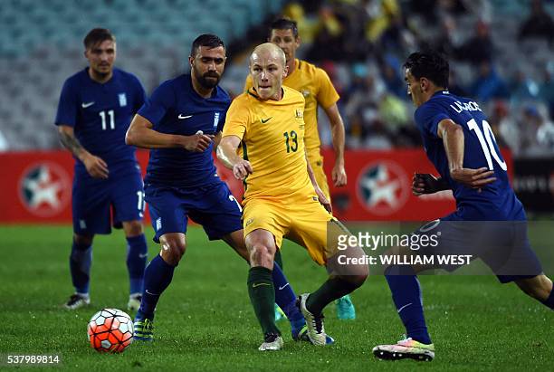 Australia's Aaron Mooy is tackled by Lazaros Christodoulopoulos of Greece in their international football friendly match played in Sydney on June 4,...