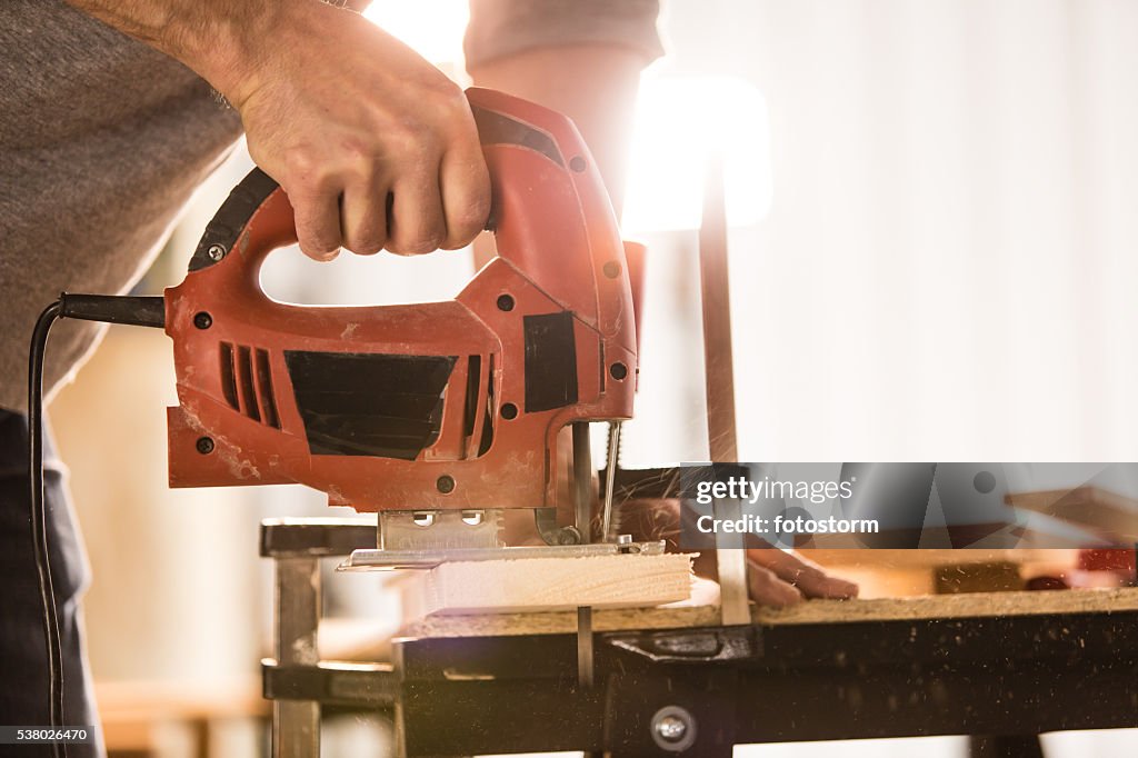 Man's hand using electric jigsaw