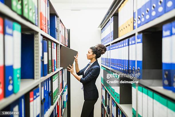 woman is searching for files in paper archive - filing cabinet stock pictures, royalty-free photos & images