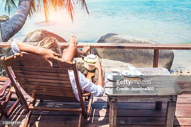 young woman enjoys drinking coffee and coconut - enjoying the beach stockfoto's en -beelden