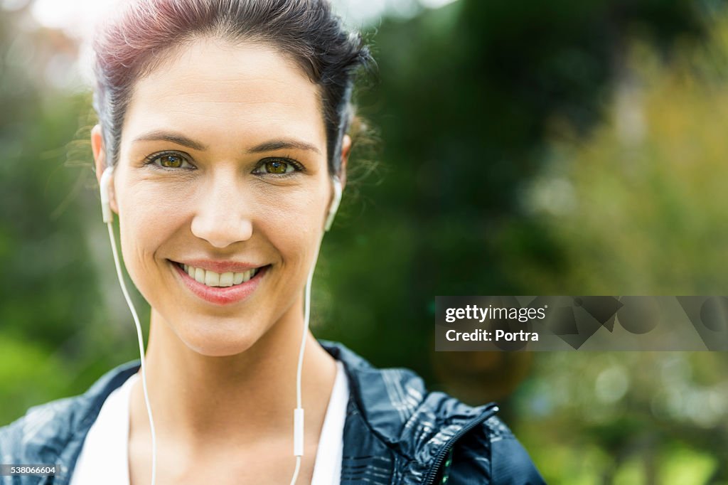 Portrait of happy woman listening to music outdoors