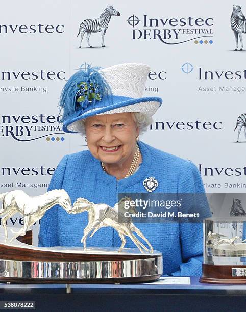 Queen Elizabeth II presents the Investec Derby trophy during Derby Day at the Investec Derby Festival, celebrating The Queen's 90th Birthday, at...