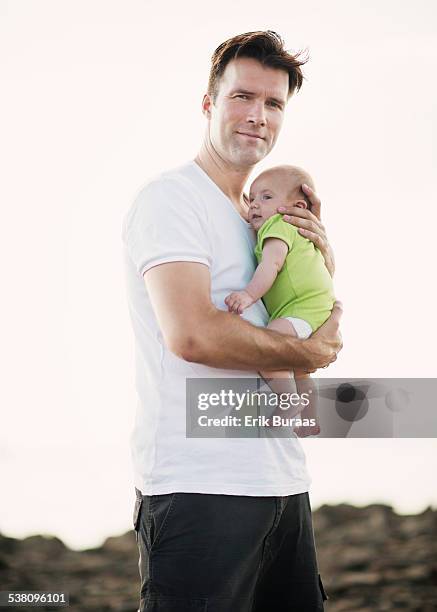 father holding baby gently in sunshine - erik buraas stock-fotos und bilder