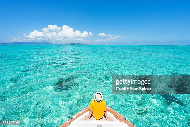 man sitting on boat sailing through tropical lagoon island paradise - okinawa prefecture stock-fotos und bilder