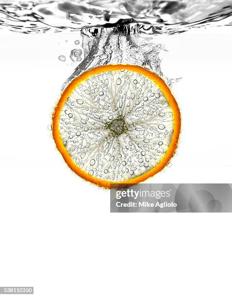 orange wedge being dropped into water - mike agliolo imagens e fotografias de stock