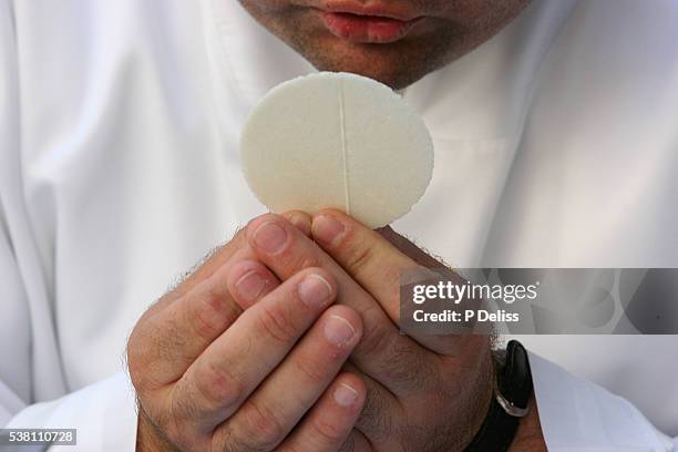 priest holding communion wafer - communion wafer stock pictures, royalty-free photos & images