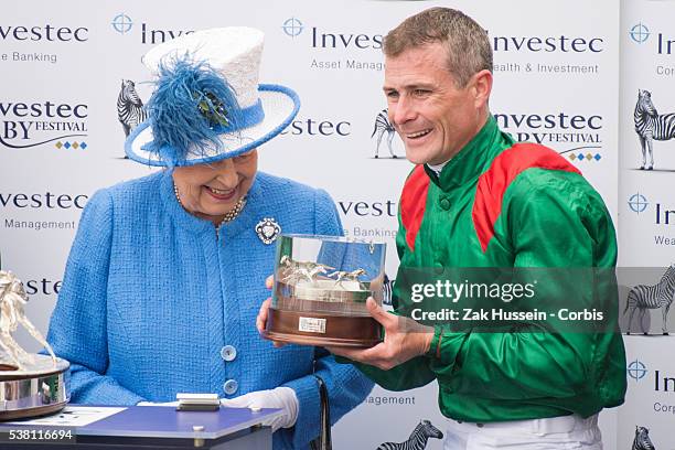 Queen Elizabeth II presents the trophy to Epsom Derby winning jockey Pat Smullen during the Investec Derby Festival at Epsom Racecourse on June 4,...