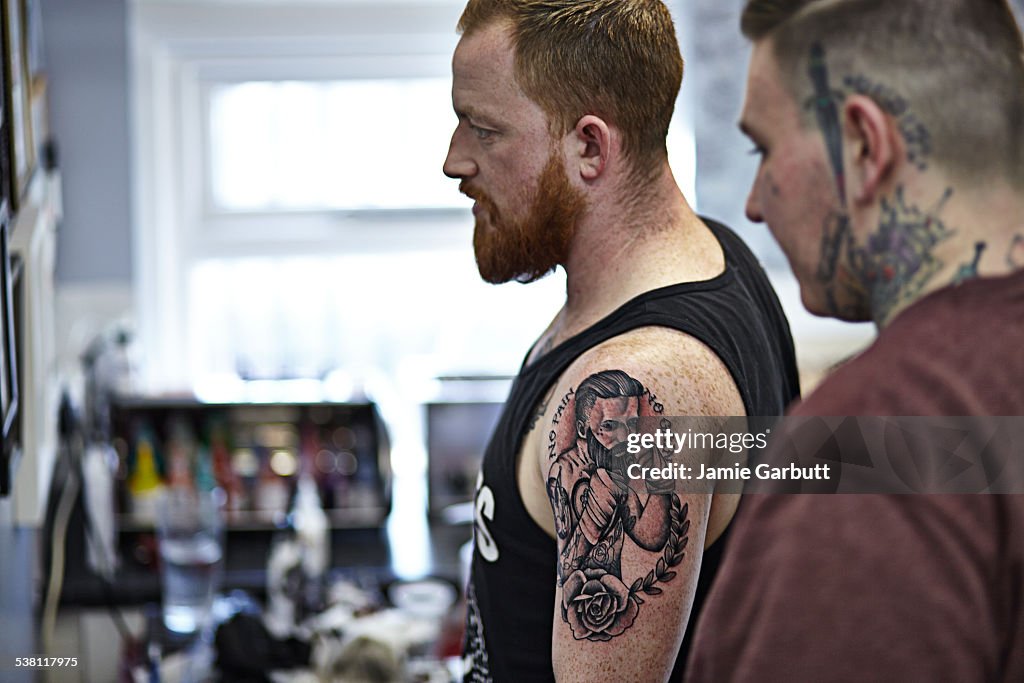 Red headed bearded male admiring new ink