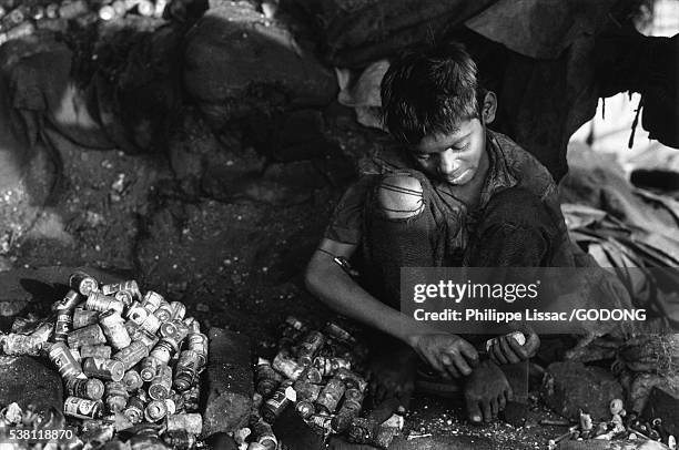child worker reclaiming metals from used batteries - trabalho infantil imagens e fotografias de stock