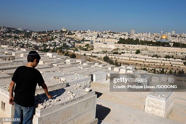 boy placing stone on grave at mount of olives jewish cemetery - gorra a modo de casquete fotografías e imágenes de stock