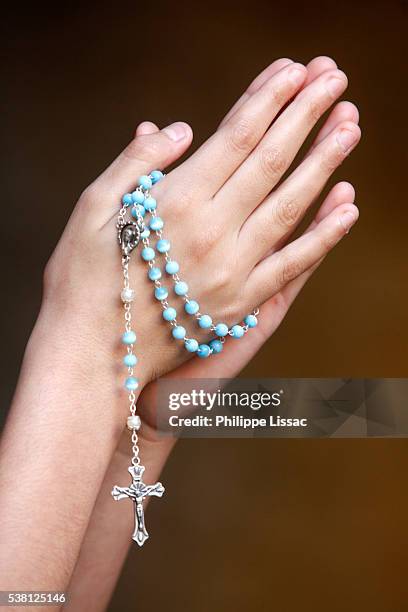 girl praying with prayer beads - rosary beads fotografías e imágenes de stock