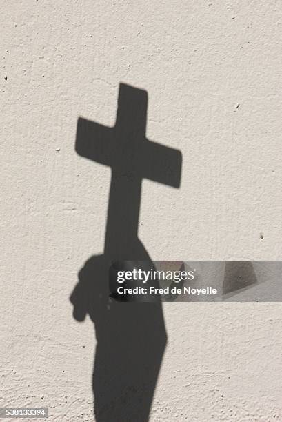 shadow of a hand holding a cross - cross section stock-fotos und bilder
