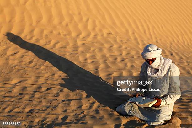 beduin reading the kuran in the sahara - bedouin stock-fotos und bilder