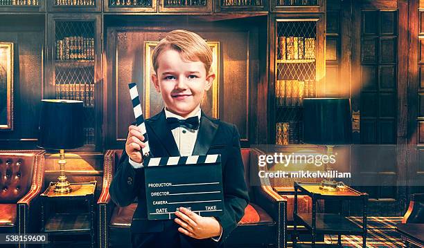 boy wears tuxedo and holds film slate on location - movie actor stock pictures, royalty-free photos & images