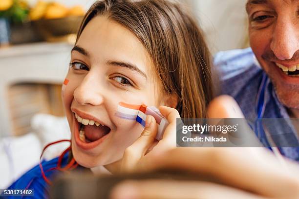 father and daughter painting face with tricolore and taking selfie - france supporter stock pictures, royalty-free photos & images