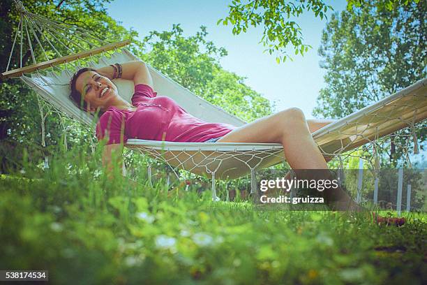 young carefree woman relaxing in a hammock in the garden - garden hammock stock pictures, royalty-free photos & images