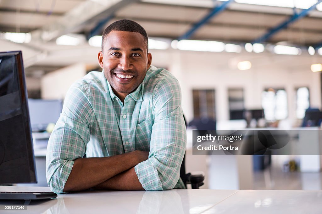 Smiling young businessman sitting at computer desk