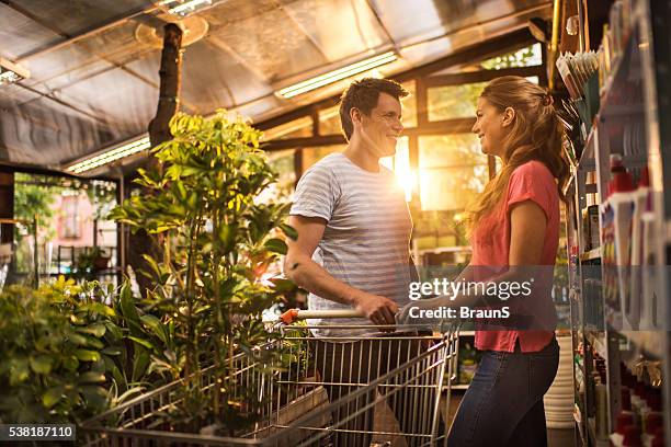 smiling couple talking to each other in a greenhouse. - young couple shopping stock pictures, royalty-free photos & images