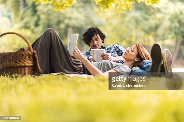 young couple relaxing with books on picnic during springtime. - laying park stock pictures, royalty-free photos & images