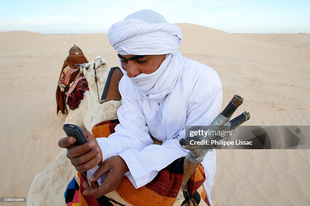 Bedouin camel rider using a mobile phone in the Sahara