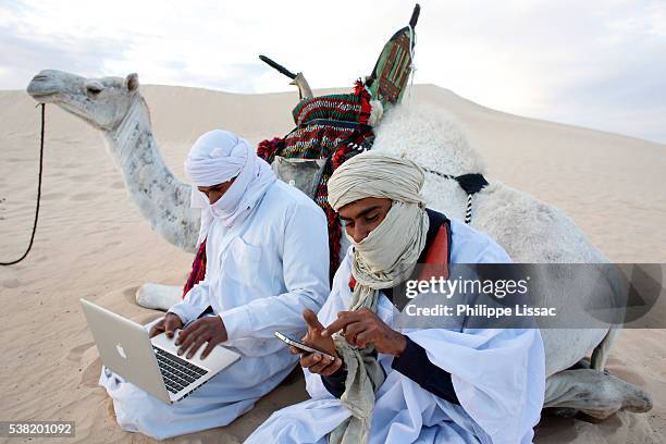 bedouins using a laptop and a cell phone in the sahara - sahara computers stock pictures, royalty-free photos & images