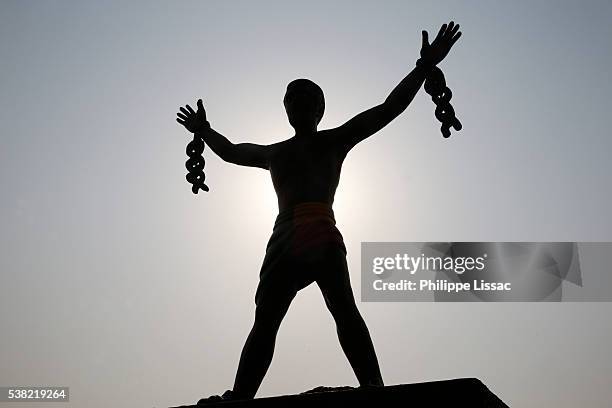 statue depicting a slave breaking his chains - sklaverei stock-fotos und bilder