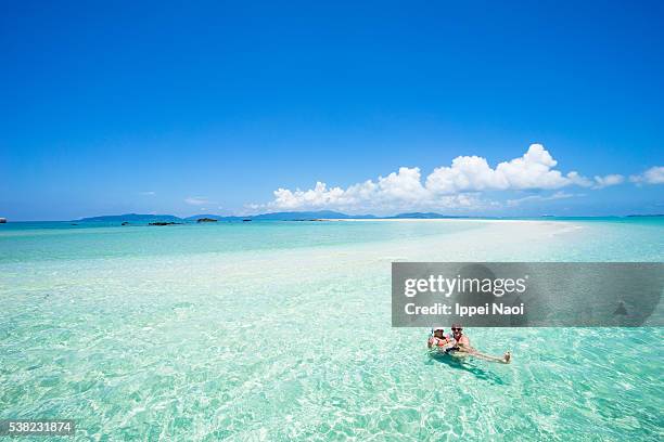 senior couple enjoying clear tropical water and coral cay, okinawa - japanese couple beach stock-fotos und bilder