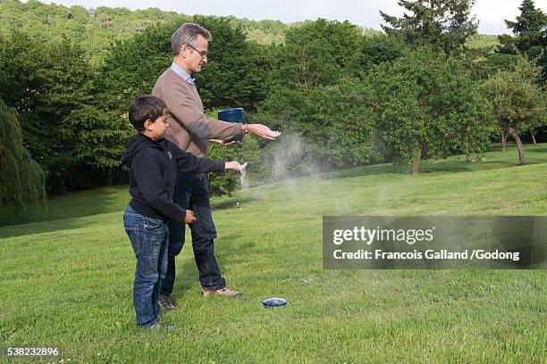 father and son scattering ashes in a garden. - decorative urn stock-fotos und bilder