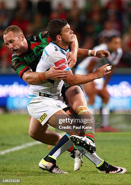 Ashley Taylor of the Titans watches his field goal kick to win the game in double extra time while being tackled by Jason Clark of the Rabbitohs...