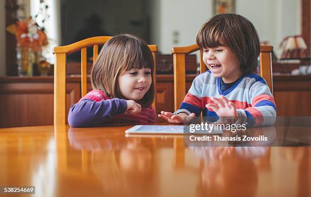 small kids using a tablet - wooden table kids stockfoto's en -beelden