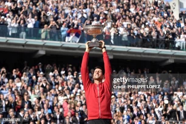 Serbia's Novak Djokovic holds the trophy after winning the men's final match against Britain's Andy Murray at the Roland Garros 2016 French Tennis...