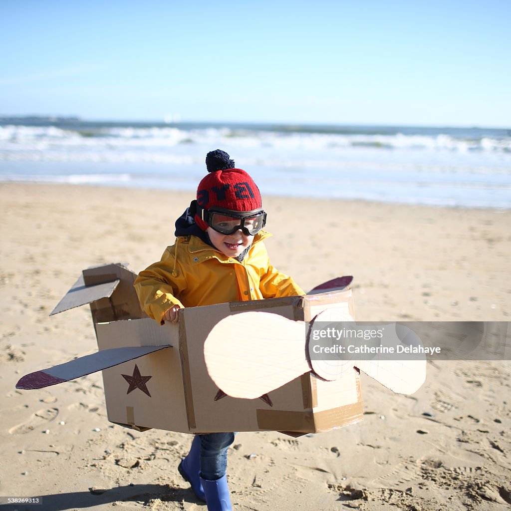 A boy playing with a plane on the beach