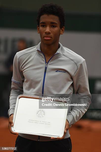 Runner up Felix Auger Aliassime of Canada poses with the trophy won during the Boys Singles final match on day fifteen of the 2016 French Open at...