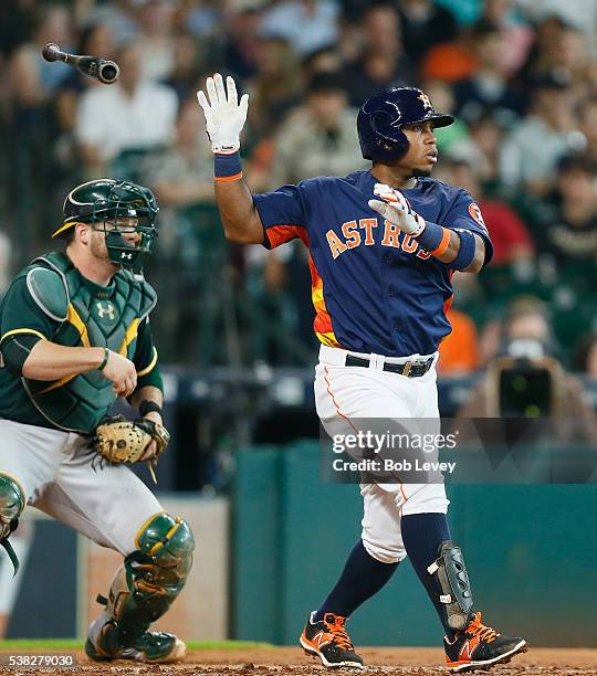 Luis Valbuena of the Houston Astros singles in the second inning as Stephen Vogt of the Oakland Athletics looks on at Minute Maid Park on June 5,...