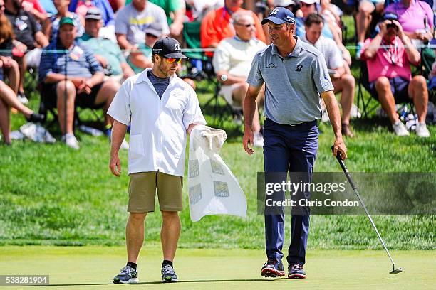 Caddie John Wood tosses a ball to Matt Kuchar on the fifth hole green after cleaning it during the final round of the Memorial Tournament presented...