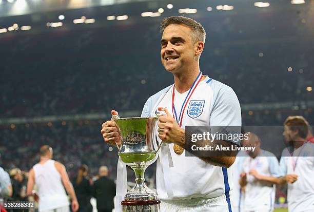 Robbie Williams of England lifts the Soccer Aid 2016 trophy after the Soccer Aid 2016 match in aid of UNICEF at Old Trafford on June 5, 2016 in...