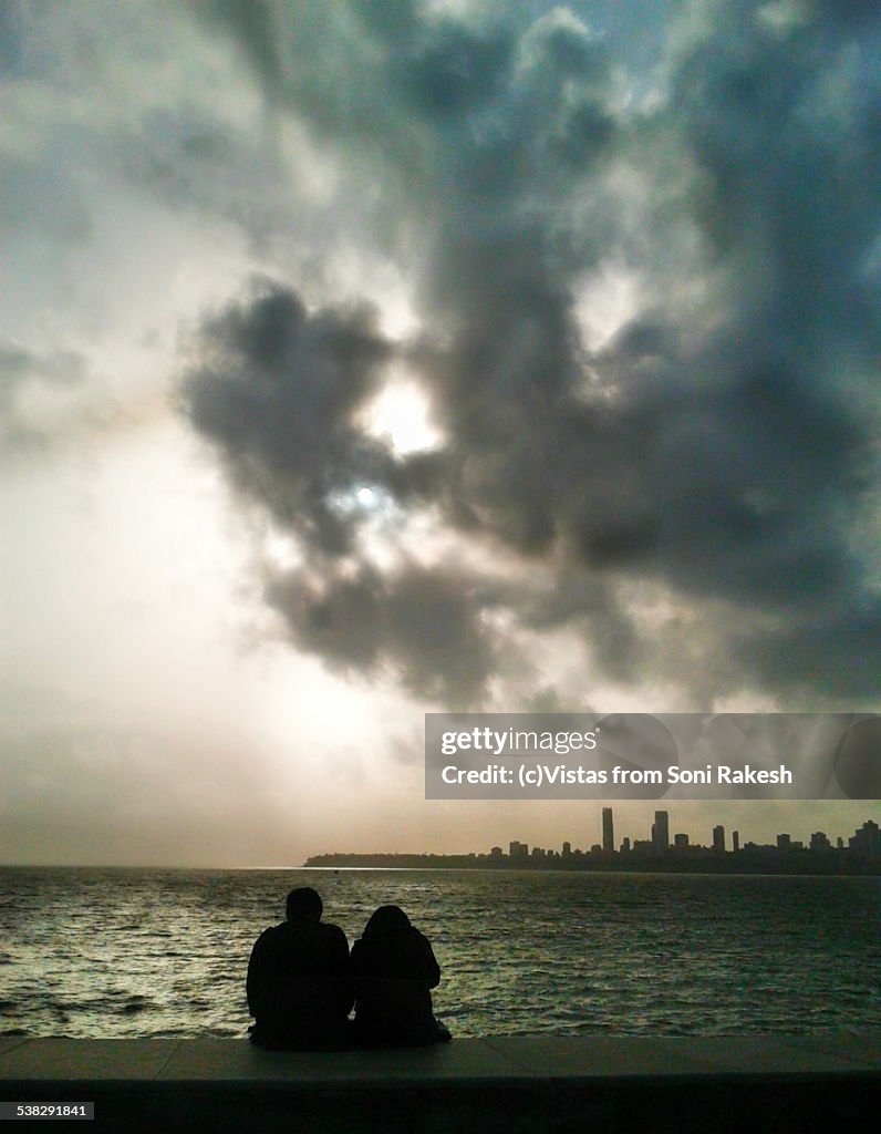 A couple looking at overcast sky over sea