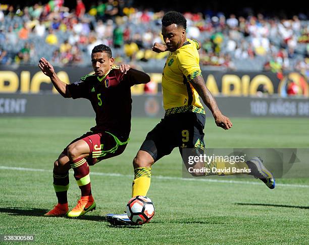 Giles Barnes of Jamaica kicks the ball as Arquimedes Figuera of Venezuela defends during the first half during a group C match between Jamaica and...