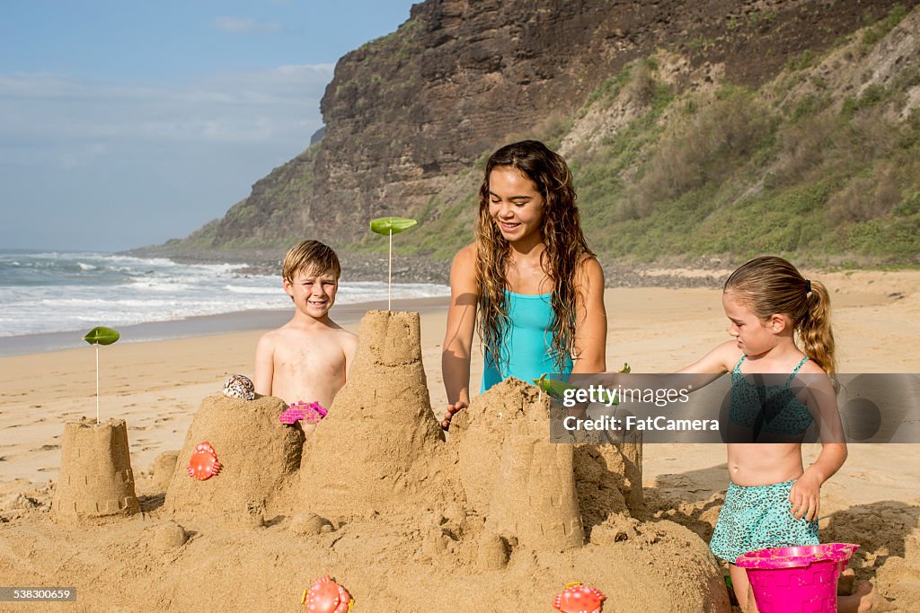 Siblings building sandcastle on vacation to a tropical destinati