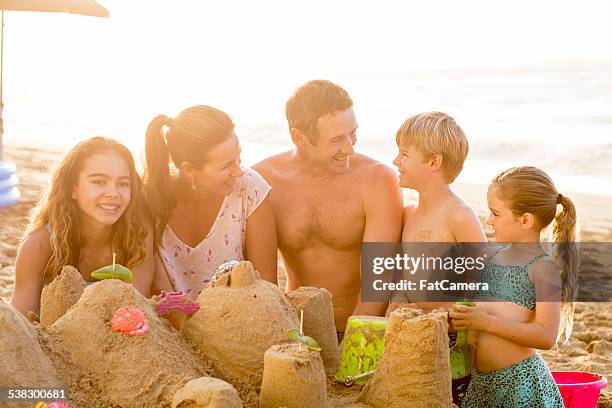 family building a sandcastle on the beach in hawaii - hawaii vacation and parent and teenager stock pictures, royalty-free photos & images