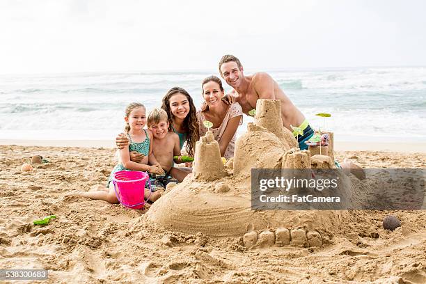 family building a sandcastle on the beach in hawaii - hawaii vacation and parent and teenager stock pictures, royalty-free photos & images