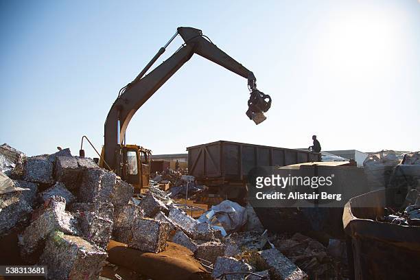 crane loading metal blocks in scrap yard - sucata imagens e fotografias de stock