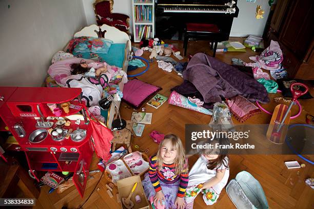 two girls smiling into the camera in chaos room - kids mess stockfoto's en -beelden