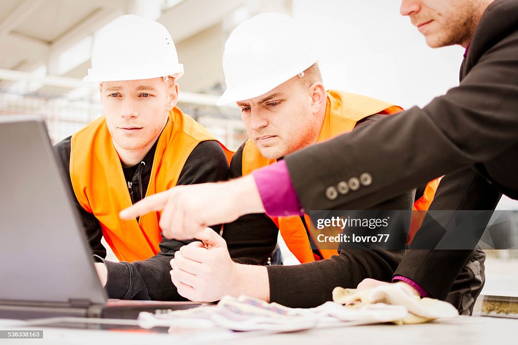 Architect pointing plans on laptop