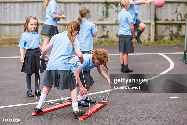 girls playing in the school yard - schooluniform stockfoto's en -beelden