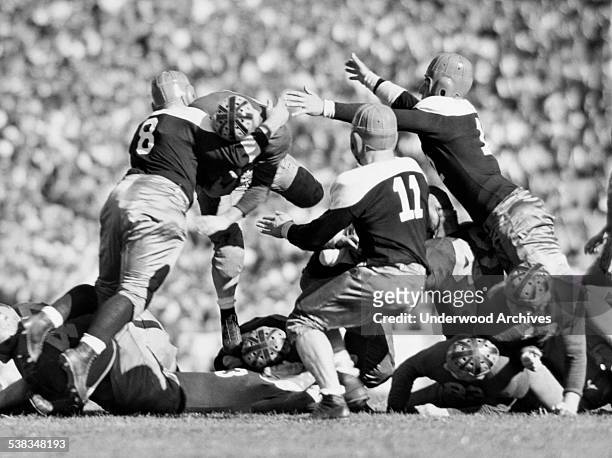University of California's 'Wild Bull' halfback, Tony Firpo, is met by three St Mary's College tacklers as he leaps over the line for a gain of a...