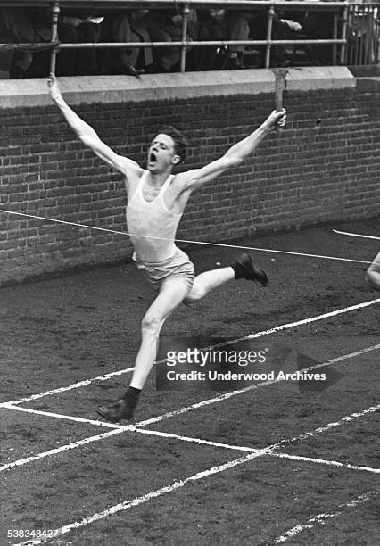 Runner in the relay event crosses the finish line at the Penn Relays Carnival, Philadelphia, Pennsylvania, 1946.